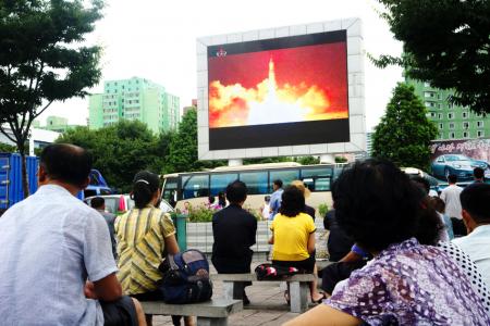People watch as coverage of an ICBM missile test is displayed on a screen in a public square in Pyongyang on July 29, 2017.