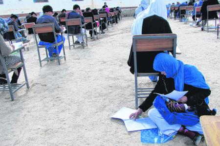 Afghan mother of three writes exam with baby on her lap
