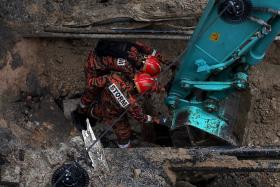 Malaysia Fire and Rescue Department officers inspecting the site where a woman fell into a sinkhole in Jalan Masjid India on Aug 23.