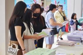 Madam Pauline Fong (third from left) and her daughters browsing assessment books at a CDAC event at Nanyang Junior College on Dec 3.