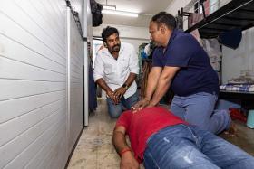 (From left) Mr Karunanithi Prabhakaran guiding Mr Ganapathi Kaliyamoorthy on how to perform cardiopulmonary resuscitation on Mr Mohan Satheesh Kumar in a demonstration.