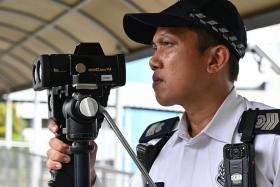 A traffic policeman using a police speed laser camera over PIE during a media showcase on Feb 22.