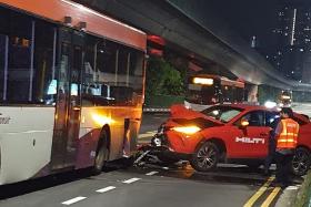 Photos of the accident show a red car with a damaged hood behind a bus with a bumper that fell on the road.