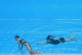 Coach Andrea Fuentes (right) swims to recover Anita Alvarez from the bottom of the pool in Budapest on June 22, 2022. 