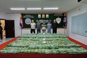 The five foreign nationals, which included a Singaporean, stand behind the drugs seized during a bust on Jan 22.