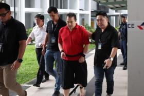 Toh Chee Hong (in red), 50, being led by the police back to the crime scene in Clementi on Oct 28.