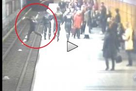 Distracted man accidentally falls off platform onto train track. Fortunately, he&#039;s saved by a transit officer in the nick of time.