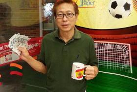 WINNER: Mr Lim Min Kwang with the World Cup collectible mug he redeemed and the $300 he won from the Weekly Draw.