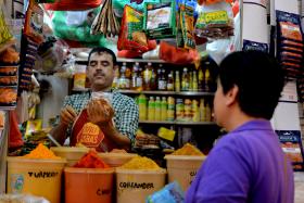 Mr Akbar Rahman (left), 44, owns a small stall selling an assortment of condiments. A customer, who wanted to be known as Rose, regularly buys his curry powder as she says it is the cheapest and best curry she knows of.