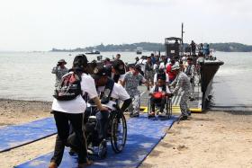 FUN OUTING: (Above) Members of the Republic of Singapore Navy helping participants board the fast craft utility boats that took them to Pulau Ubin.