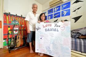 MEMORIES:  Mr Daniel Tan&#039;s parents holding up the tribute made by his friends that was displayed during his funeral wake last week.