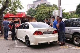CAUGHT: Malaysian police officers arrest the man (circled) who is believed to have stolen Mr Joe Ong’s Honda Civic.