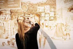 TALENTED: Mrs Maria Filatova-Chan working on a wall mural illustrating contemporary coffee culture in Singapore. The mural is featured at the Coffee Art and Appreciation Exhibition at Temasek Polytechnic.