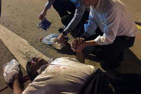 HELP CAME FAST: Mr Chen and Dr Liew aiding the injured man, who was bleeding from a cut on the back of his head.