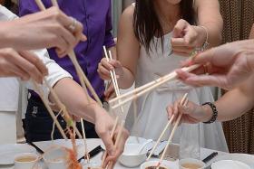 JOY: Bowler of the Year Shayna Ng (left) and Youth Bowler of the Year Joey Yeo (right) tossing the yusheng as they celebrate the appointment of Francis Yeo  as the new acting national coach.