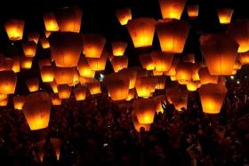 UPLIFTING: (Above) People release sky lanterns as a form of prayer for good luck and blessings. Some 200 lanterns were released each time at 15 minute intervals and a total of 1,600 were released that night.
