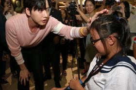 BIG HEART: Student Lim Qi Hui (right) was shoved to the ground when fans pushed forward to shake hands with Korean actor Park Hae Jin (in pink), and was helped up and comforted by him. 