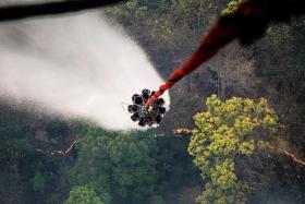 WATERWORKS: The Chinook is flown to a water source and a heli-bucket - which can hold up to 5,000 litres of water - is lowered to collect water for dousing flames at a hotspot.