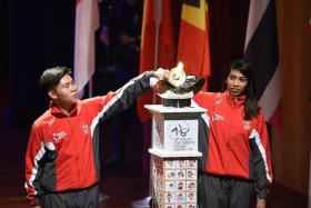 KICKING THINGS OFF: Singapore archer Ang Han Teng (left) and silat exponent Nur Shafiqa (right) lighting the cauldron to mark the start of the 18th Asean University Games.