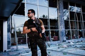 ON ALERT: An armed Turkish police officer standing guard in front of the damaged police headquarters after it was bombed during the failed coup attempt.