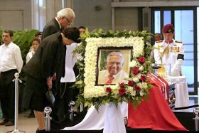 Preisdent Tony Tan Keng Yam and his wife Madam Mary Chee bow in front of Mr S R Nathan&#039;s casket at Parliament House.