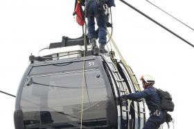 SAFE: An SCDF rescuer making his way to the top of the cable car. Another rescuer rappels down to the cable car and hooks the &#039;casualty&#039; onto a harness. Then they lower &#039;him&#039; down. 