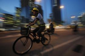 A migrant worker cycles home at dusk after a day&#039;s work.