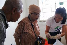 Mr Abdul Wahab Sarman (left) and his wife (centre) sorting through their belongings with a Habitat for Humanity volunteer (right).