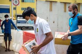 Tampines Rovers midfielder Yasir Hanapi (left) and assistant coach Mustafic Fahrudin transporting cartons of dates to foreign workers yesterday.