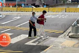Student helps older man with white cane to safely cross busy road