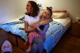 Ukrainian refugee Alexandra Zhuravel, 38, holds her daughter Alevtina Bravorichenko-Crane, 8, in their bedroom at the Benedictine Sisters Monastery, which has welcomed refugees amid Russia's invasion of Ukraine, in Jaroslaw, Poland, March 22, 2022.