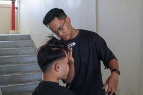 Muhammad Hazim Hanif, 23, cuts his friend&#039;s hair in the comfort of the lift lobby of his home.