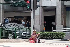 The man was seen sitting in the middle of a pedestrian crossing in front of Bugis Junction.