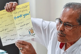 Mr Umar showing the thank-you card given to him nearly 20 years ago by the family of the boy he saved. 