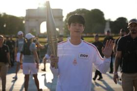 BTS singer Jin carrying the Paris Olympics torch in Paris on July 14.