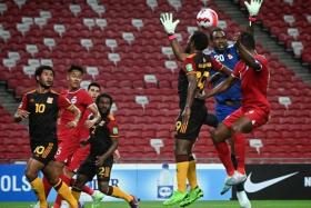 Papua New Guinea goalkeeper Ronald Warisan (in blue) and defender Joshua Talau in an aerial challenge with Singapore captain Hariss Harun.