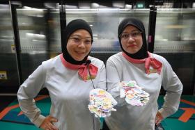 SMRT train service ambassadors Ayati Hassan (left) and Marfadina Mohamed Nossi give out stickers daily to children at Stadium MRT station.