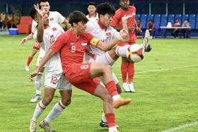 Singapore captain Harhys Stewart challenging for the ball against Vietnamese opponents as teammate Abdul Rasaq looks on.