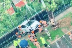 SCDF officers surrounding a car that appears to be perched on the edge of a pavement in Lorong 8 Toa Payoh.