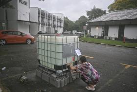 Ms Lim, a tenant and owner of a yoga studio, collecting water from a water tank to use for flushing, in Phoenix Park on Jan 13.