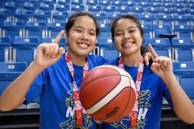 Twins Jovia (left) and Jovie Teo combined to lead Nanyang Girls' High School to their second straight C Division basketball title.